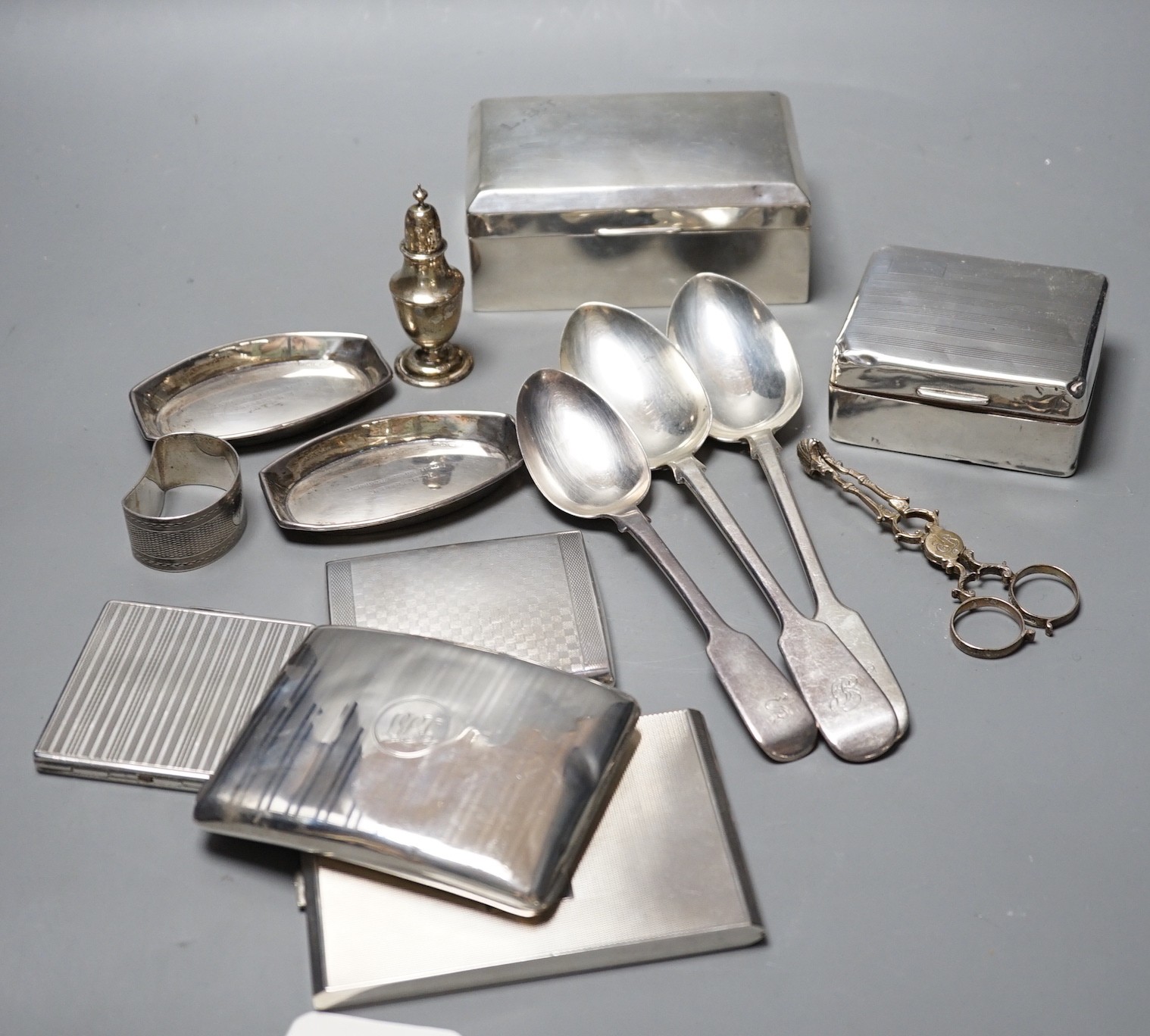 Mixed silver or white metal items including two cigarette boxes, three cigarette cases, cutlery, condiment and a napkin ring, gross